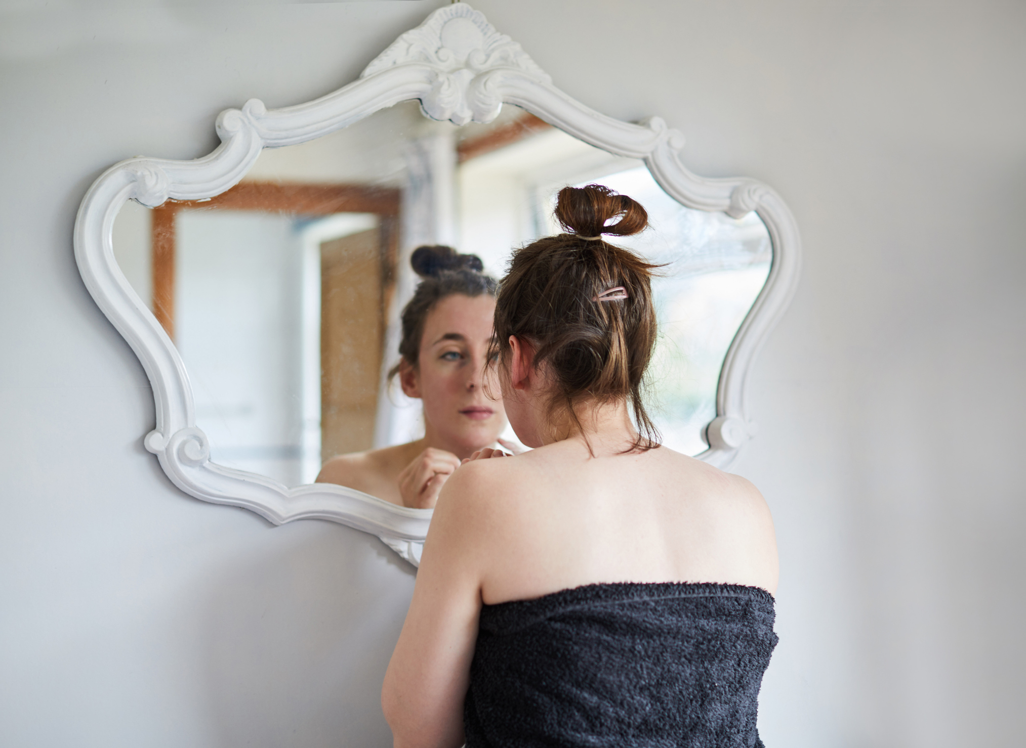 Woman examining her face in the mirror