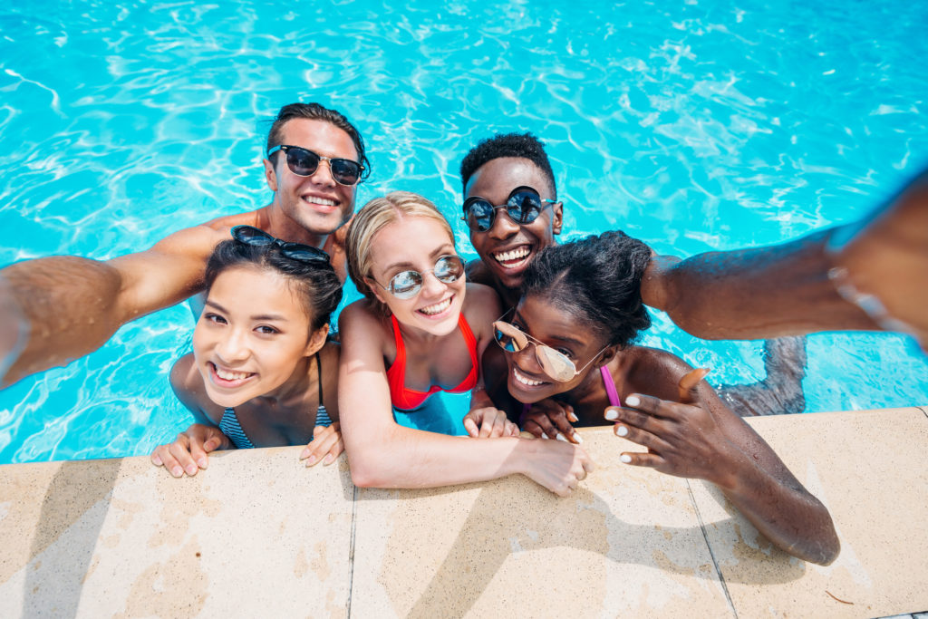 Group of young happy people taking selfie in swimming pool