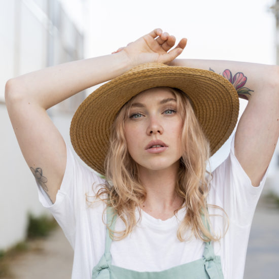 A woman with a white shirt, blond hair and a straw hat