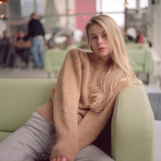 A blonde girl is sitting on a couch