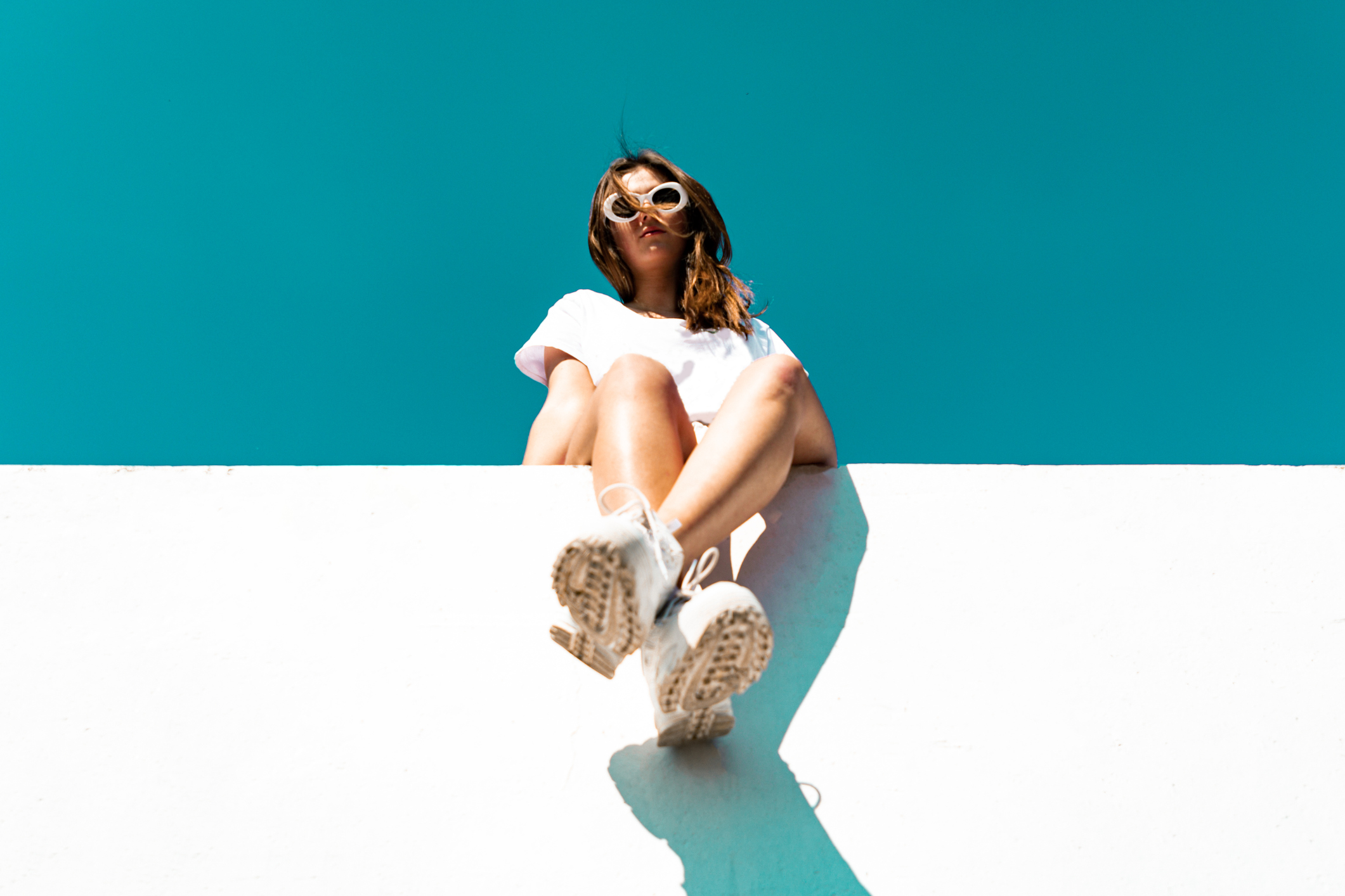 A woman sitting on a roof with a white shirt