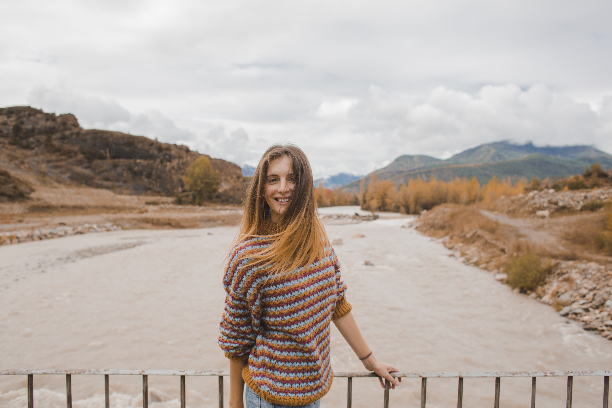 A girl takes a picture on a bridge with a river as a background