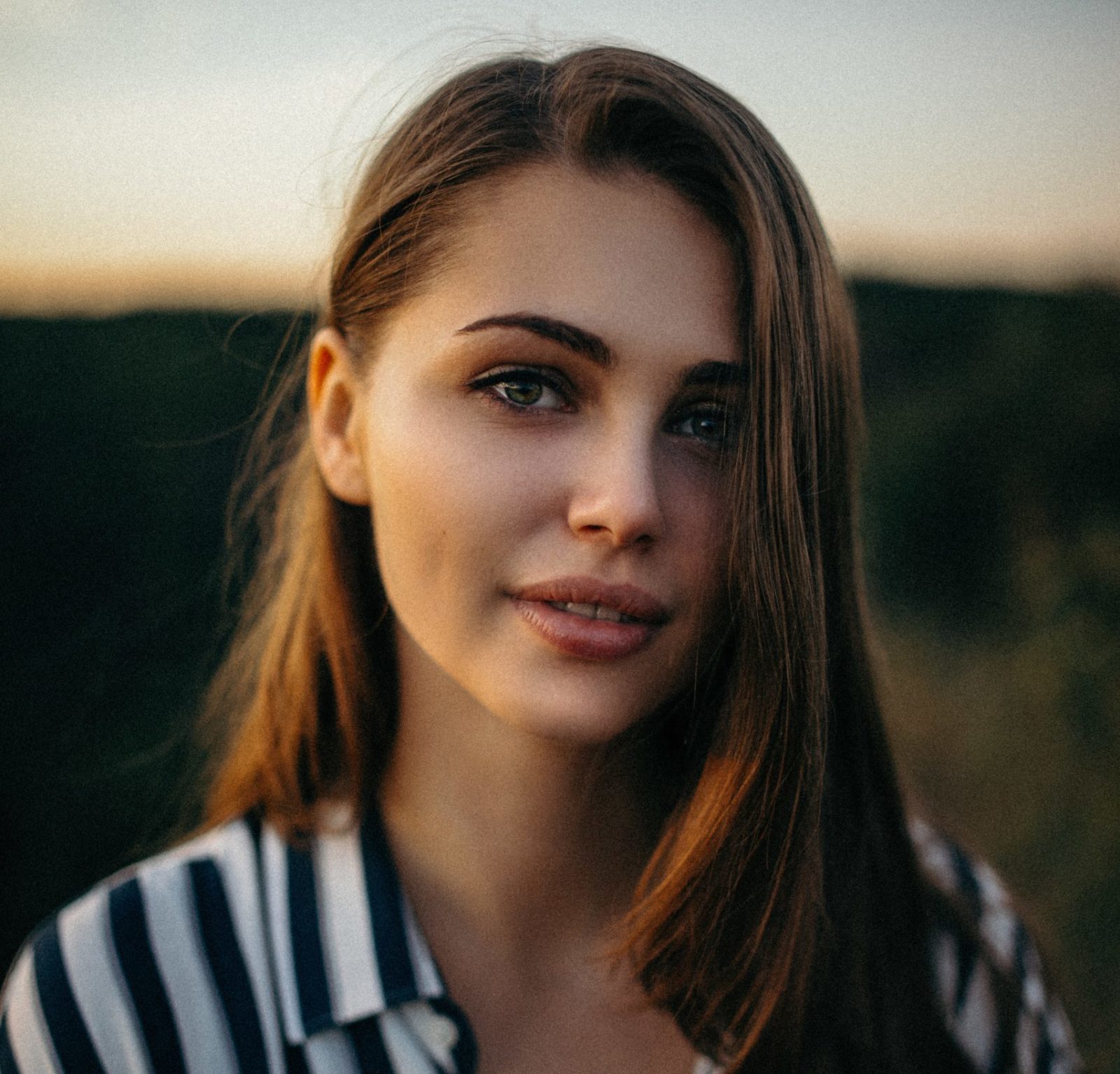 A girl with straight hair on a sunset background