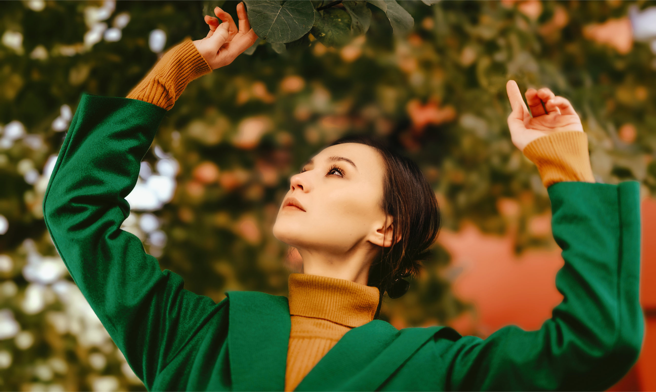 A woman with a green jacket in the background of leaves