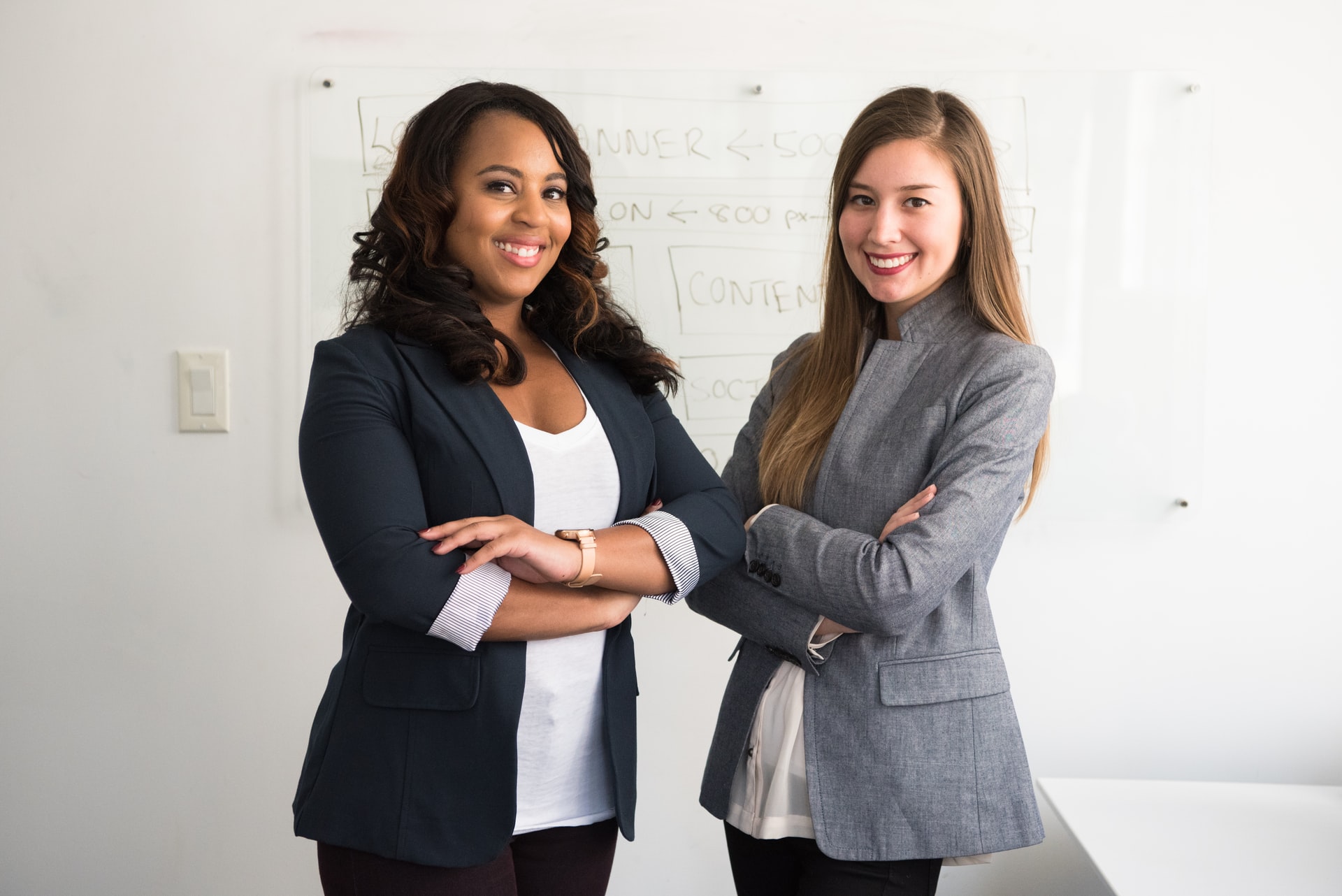 Two women join hands and smile at the camera