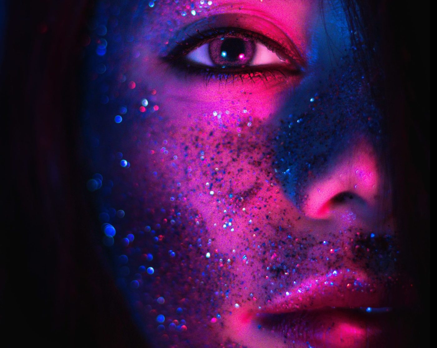 A person's face with glitter in all kinds of colors