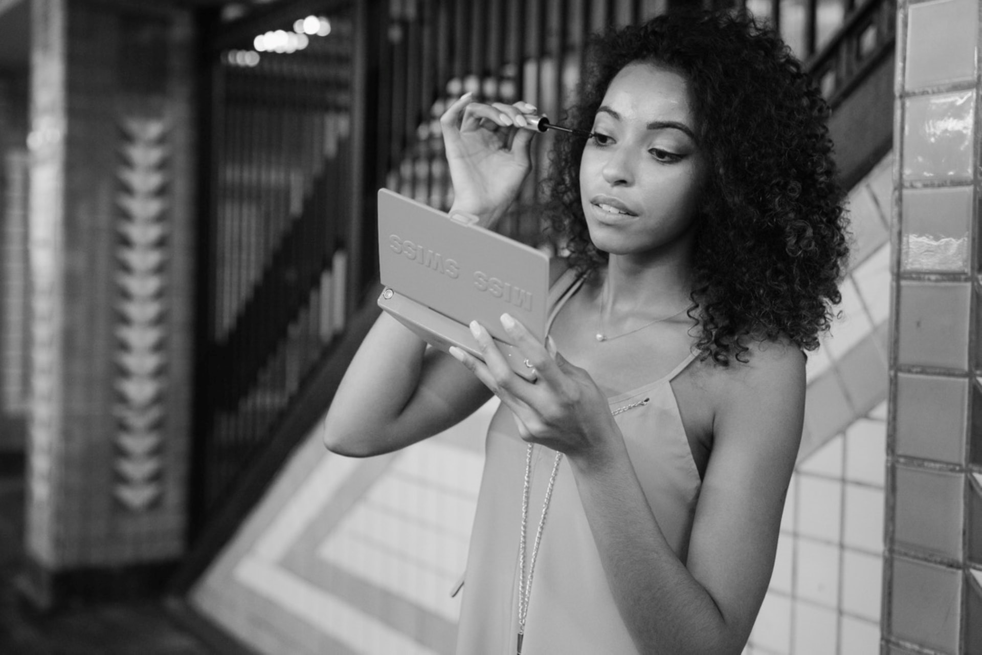 A woman with curly black hair is applying make-up to herself